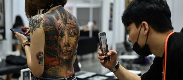 (FILES) In this file photo taken on November 29, 2019, a man takes pictures of a woman with tattoos during the International Malaysia Tattoo Expo in Kuala Lumpur - Sputnik International