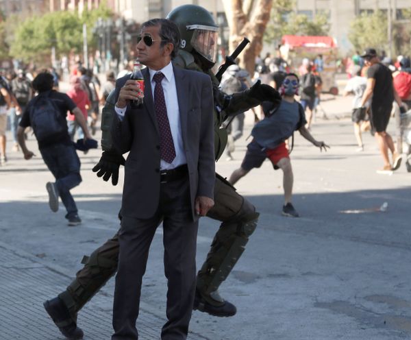 A man drinks a Coca Cola as a policeman chases demonstrators during a protest against Chile's government in Santiago, Chile December 4, 2019. A man drinks a Coca Cola as a policeman chases demonstrators during a protest against Chile's government in Santiago, Chile December 4, 2019. - Sputnik International