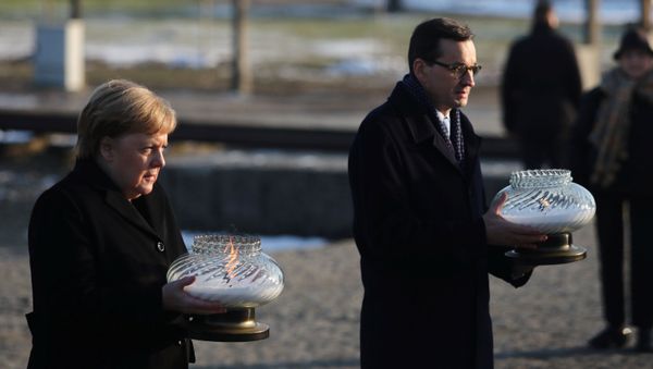 Polish Prime Minister Mateusz Morawiecki and German Chancellor Angela Merkel hold candles at the Monument to the Victims at the former Nazi German concentration and extermination camp Auschwitz II-Birkenau near Oswiecim, Poland December 6, 2019. - Sputnik International