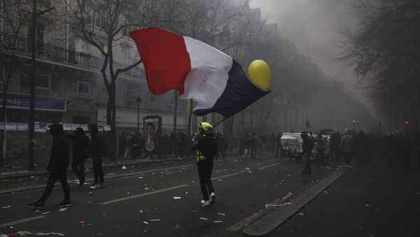 A man waves a French flag during a demonstration in Paris, Thursday, Dec. 5, 2019. Small groups of protesters are smashing store windows, setting fires and hurling flares in eastern Paris amid mass strikes over the government's retirement reform. A man waves a French flag during a demonstration in Paris, Thursday, Dec. 5, 2019. Small groups of protesters are smashing store windows, setting fires and hurling flares in eastern Paris amid mass strikes over the government's retirement reform. - Sputnik International