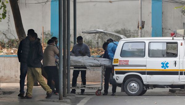 Hospital staff wheels the body of a victim of a fire that swept through a factory where laborers were sleeping, to a mortuary in New Delhi, India December 8, 2019.  - Sputnik International