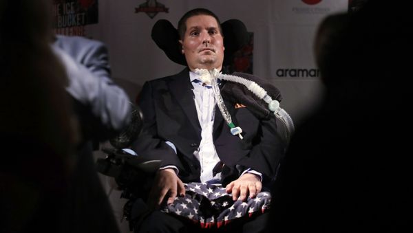   --FILE-- In this Sept. 18, 2017 photograph, Pete Frates, who is stricken with amyotrophic lateral sclerosis, or ALS, and is the inspiration of the Ice Bucket Challenge, listens to a guest at Fenway Park in Boston. - Sputnik International
