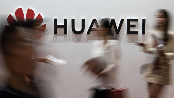 (FILES) In this file photo taken on August 2, 2019 people walk past a Huawei logo during the Consumer Electronics Expo in Beijing. - Chinese tech giant Huawei, facing US criminal charges and economic sanctions, is planning to relocate its telecommunications research from the United States to Canada, founder Ren Zhengfei said in an interview published on December 3, 2019 - Sputnik International