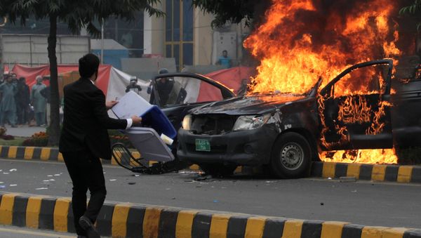 A lawyer throws trash bin towards police near a vehicle set on fire outside the Punjab Institute of Cardiology (PIC) in Lahore, Pakistan December 11, 2019 - Sputnik International