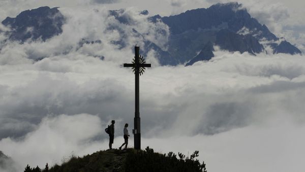 Hikers enjoy the view from the peak Hoher Fricken (1,940 metres) in front of Germany's highest mountain Zugspitze (2,962 metres, R) in the Alps near the village of Garmisch-Partenkirchen, in southern Germany. - Sputnik International