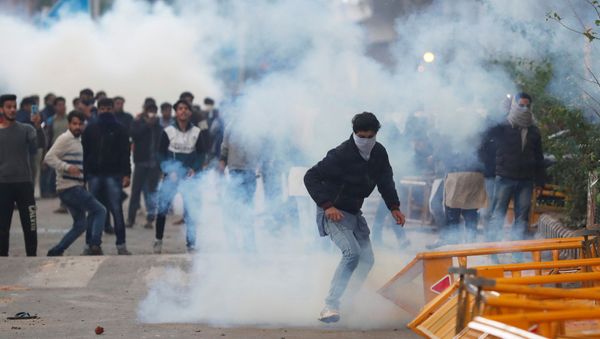 Protesters run for cover amid tear gas fired by police during a protest against the Citizenship Amendment Act, which seeks to give citizenship to religious minorities persecuted in neighbouring Muslim countries, outside the Jamia Millia Islamia University in New Delhi, India, 13 December 2019 - Sputnik International