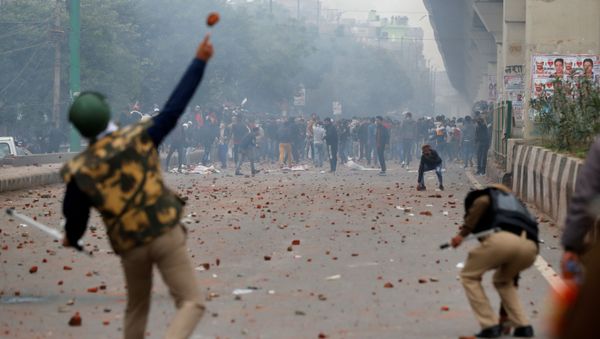 A riot police officer throws a piece of brick towards demonstrators during a protest against a new citizenship law in Seelampur, area of Delhi, India  December 17, 2019 - Sputnik International
