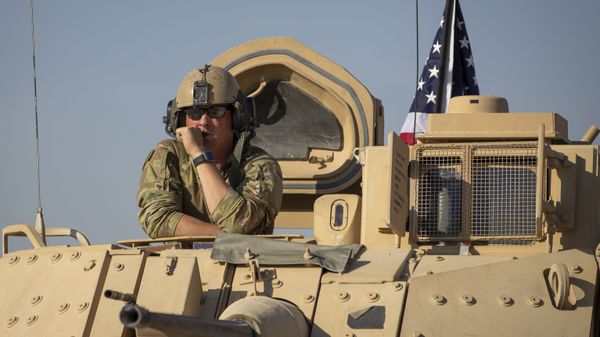 A U.S. soldier observes form the top of a fighting vehicle at a US military base at undisclosed location in Northeastern Syria - Sputnik International