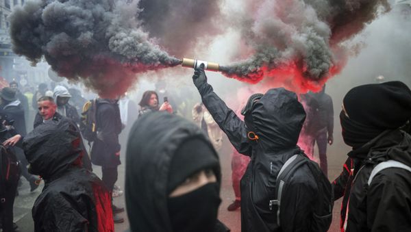 A protester holds up a flare during a demonstration in Lyon, central France, Tuesday, Dec. 17, 2019. Workers at the Eiffel Tower, teachers, doctors, lawyers and people from across the French workforce walked off the job Tuesday to resist a higher retirement age, or to preserve a welfare system they fear their business-friendly president wants to dismantle. (AP Photo/Laurent Cipriani) - Sputnik International