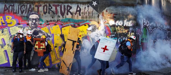 Medical volunteers move amid tear gas during a protest against Chile's government in Santiago, Chile December 20, 2019 - Sputnik International
