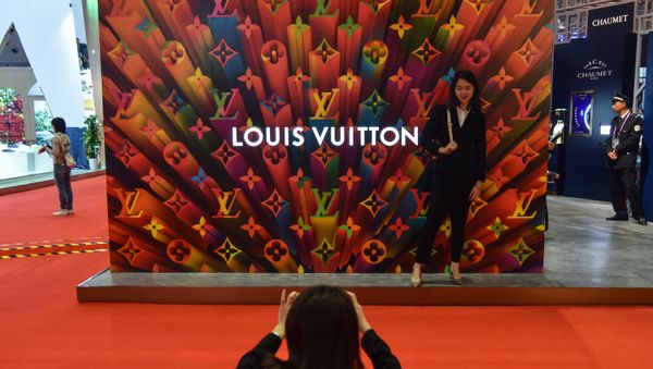 A woman poses for a picture next to a Louis Vuitton stand during the second China International Import Expo in Shanghai on november 6, 2019. A woman poses for a picture next to a Louis Vuitton stand during the second China International Import Expo in Shanghai on november 6, 2019. - Sputnik International