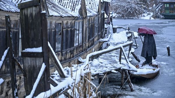 A man removes snow from a boat on the banks of the the Dal Lake during a snowfall in Srinagar on January 13, 2020 - Sputnik International