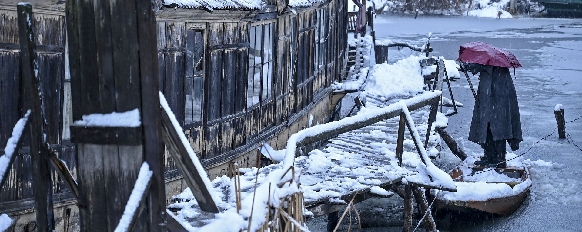 A man removes snow from a boat on the banks of the the Dal Lake during a snowfall in Srinagar on January 13, 2020 A man removes snow from a boat on the banks of the the Dal Lake during a snowfall in Srinagar on January 13, 2020 - Sputnik International, 1920, 14.01.2020