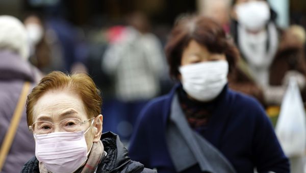Pedestrians wear protective masks as they walk through a shopping district in Tokyo Thursday, Jan. 16, 2020. Japan's government said Thursday a man treated for pneumonia after returning from China has tested positive for the new coronavirus identified as a possible cause of an outbreak in the Chinese city of Wuhan.  - Sputnik International