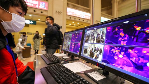 A staff member wearing a mask monitors thermal scanners that detect temperatures of passengers at the security check inside the Hankou Railway Station in Wuhan, Hubei province, China January 21, 2020 - Sputnik International