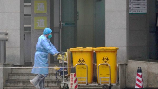 FILE - In this Wednesday, Jan. 22, 2020, file photo, a staff member moves bio-waste containers past the entrance of the Wuhan Medical Treatment Center in Wuhan, China, where some people infected with a new virus are being treated. FILE - In this Wednesday, Jan. 22, 2020, file photo, a staff member moves bio-waste containers past the entrance of the Wuhan Medical Treatment Center in Wuhan, China, where some people infected with a new virus are being treated. - Sputnik International