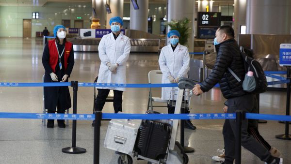 Medical officials monitor a thermal scanner as passengers arrive at the airport in Changsha, Hunan Province - Sputnik International