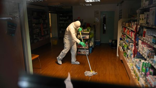 A worker in protective clothing, including face mask and gloves, is pictured cleaning the floor of the pharmacy attached to The County Oak Medical Centre in Brighton, southern England on February 10, 2020 - Sputnik International