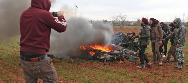Syrian rebel fighters gather around the burning remains of a military helicopter after it was shot down over the village of Qaminas, about 6 kilometres southeast of Idlib city in northwestern Syria on February 11, 2020 Syrian rebel fighters gather around the burning remains of a military helicopter after it was shot down over the village of Qaminas, about 6 kilometres southeast of Idlib city in northwestern Syria on February 11, 2020 - Sputnik International