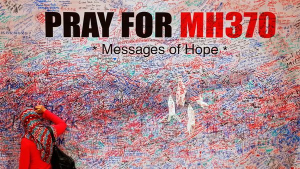A woman leaves a message of support and hope for the passengers of the missing Malaysia Airlines MH370 in central Kuala Lumpur March 16, 2014 - Sputnik International