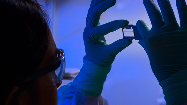 This photograph depicted an Enteric Diseases Laboratory Branch (EDLB) public health scientist, holding up a glass slide used for a run on a sequencing machine. - Sputnik International