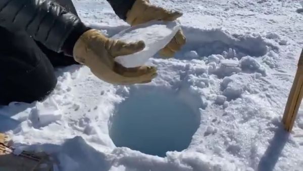 A geologist prepares to throw an ice core deep down a 450-foot borehole in Antarctica. - Sputnik International