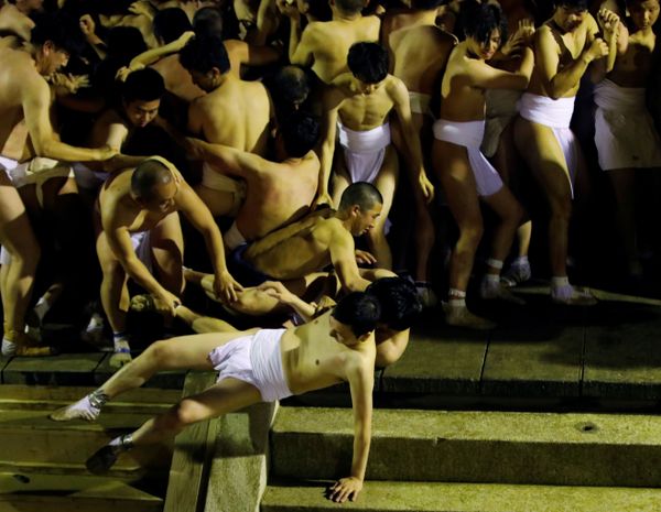 Men dressed in loincloths fall as they try to snatch a wooden stick Men dressed in loincloths fall as they try to snatch a wooden stick - Sputnik International