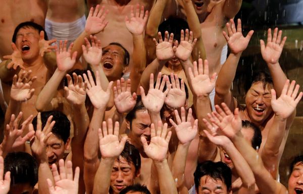 Men dressed in loincloths react as a priest splashes water on them before they prepare to snatch a wooden stick Men dressed in loincloths react as a priest splashes water on them before they prepare to snatch a wooden stick - Sputnik International