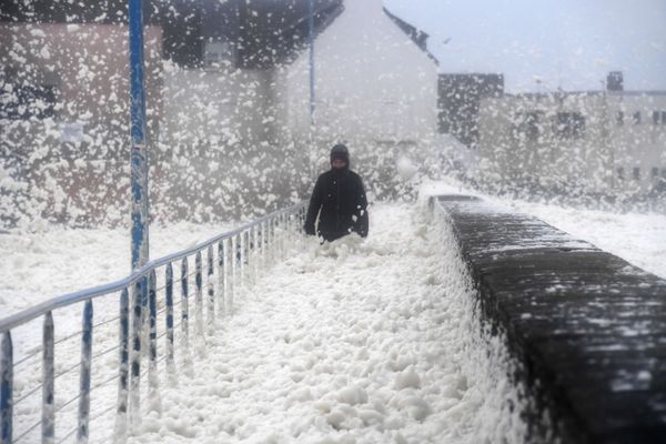 A person walks as seafoam washes up on the front walk in Saint-Guenole, western France, as storm Dennis sweeps across Brittany, on February 16, 2020.  - Sputnik International