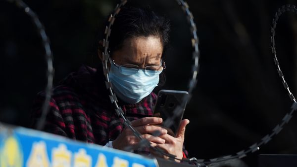 FILE PHOTO: A woman uses her mobile phone behind barbed wire at an entrance of a residential compound in Wuhan FILE PHOTO: A woman uses her mobile phone behind barbed wire at an entrance of a residential compound in Wuhan - Sputnik International