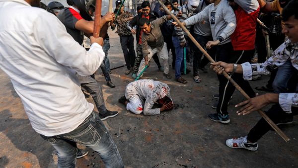 People supporting the new citizenship law beat a Muslim man during a clash with those opposing the law in New Delhi, India, February 24, 2020 - Sputnik International