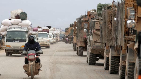 A man rides on a motorbike past Turkish military vehicles in Hazano near Idlib, Syria, February 11, 2020. REUTERS/Khalil Ashawi - Sputnik International
