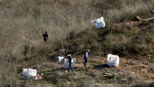 Personnel collect debris while working with investigators at the helicopter crash site of NBA star Kobe Bryant in Calabasas, California - Sputnik International