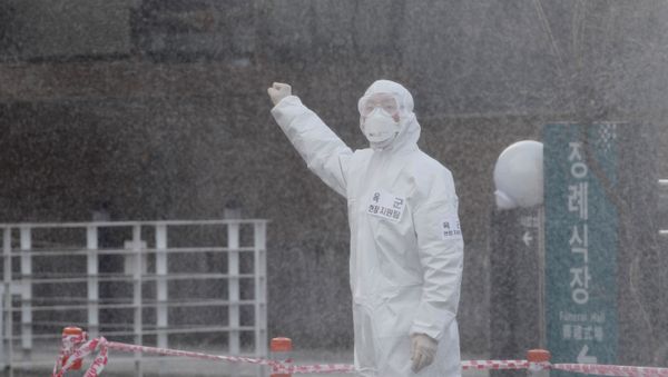 A South Korean solider in protective gear gives a sign to his colleague as they spray disinfectant on visiting cars at a 'drive-thru' testing center for the novel coronavirus disease of COVID-19 in Yeungnam University Medical Center in Daegu - Sputnik International
