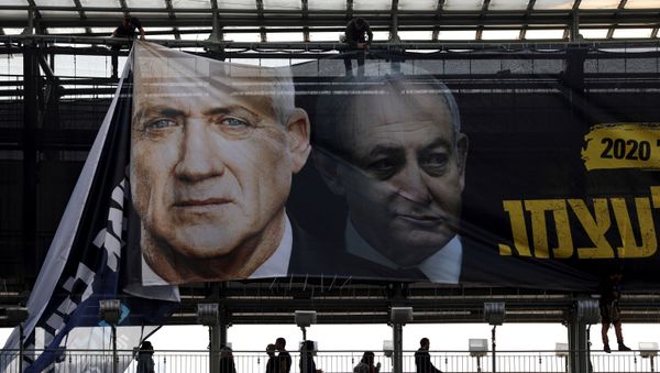 Labourers hang a banner depicting Benny Gantz, leader of Blue and White party, and Israel Prime minister Benjamin Netanyahu, as part of the party's campaign ahead of the upcoming election, in Tel Aviv, Israel February 17, 2020.  - Sputnik International