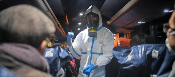 FILE - In this Feb. 2, 2020 file photo, a military officer wearing a protective suit gives instructions to evacuees from Wuhan, China, as they travel to a hospital after their arrival at a military base in Wroclaw, Poland FILE - In this Feb. 2, 2020 file photo, a military officer wearing a protective suit gives instructions to evacuees from Wuhan, China, as they travel to a hospital after their arrival at a military base in Wroclaw, Poland - Sputnik International