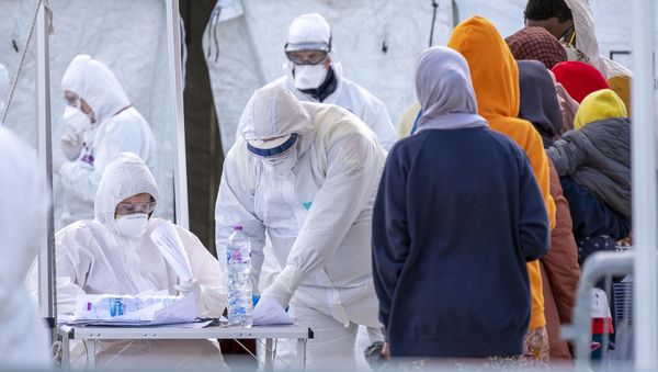 Italian Red Cross' agents wearing protective suit and mask register migrants rescued in the Mediterranean as they disembark from the Sea Watch NGO's ship on 27 February 2020 in the port of Messina, Sicily. - Migrants are checked for COVID-19 as they disembark from the NGO Sea Watch in the port of Messina. - Sputnik International