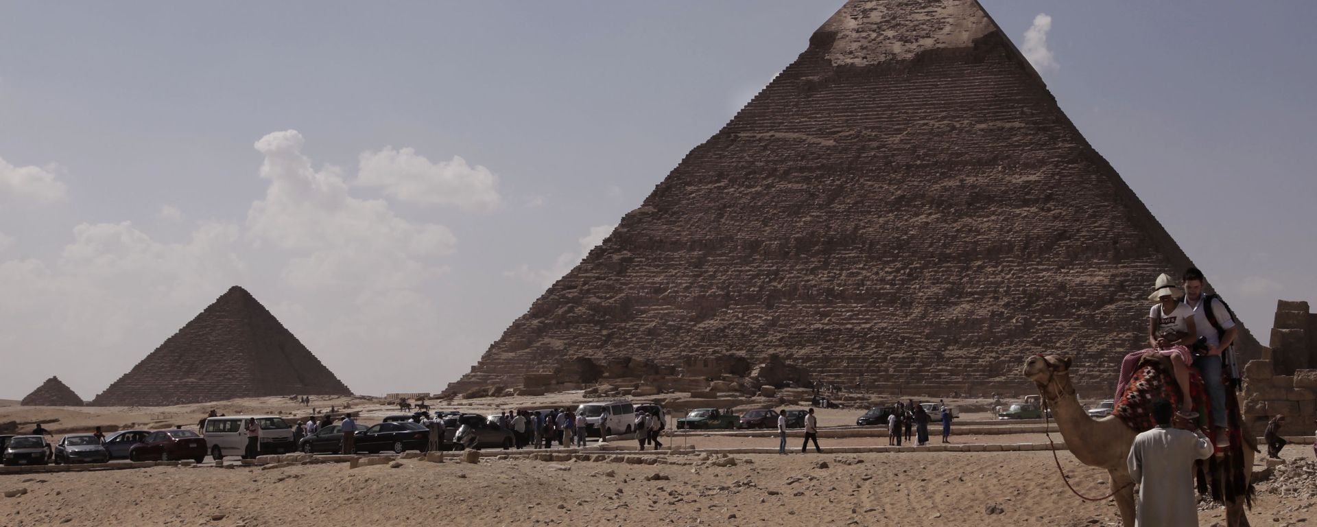 Tourists ride a camel as they visit the historical site of the Giza Pyramids, in front of the Khafre pyramid, right, near Cairo, Egypt. File photo. - Sputnik International, 1920, 31.07.2025