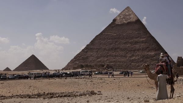 Tourists ride a camel as they visit the historical site of the Giza Pyramids, in front of the Khafre pyramid, right, near Cairo, Egypt. File photo. - Sputnik International