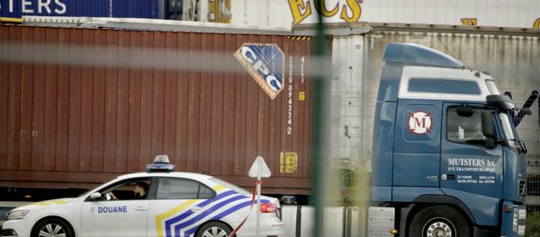 A customs police car parks next to a truck waiting to pass through a scanning tunnel at the Port of Zeebrugge, in Zeebrugge, Belgium, Thursday, Oct. 24, 2019. British police raided two sites in Northern Ireland and questioned a truck driver as they investigate the deaths of 39 people found in a truck container that they believe came from Zeebrugge and was then found at an industrial park in southeastern England. - Sputnik International