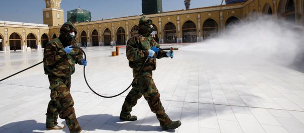 Members of the civil defense team spray disinfectant to sanitize surrounding of the Kufa mosque - Sputnik International