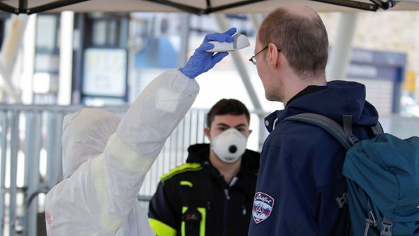 A person wearing a protective suit and mask checks the temperature of people departing from the ferry port of Molo Beverello after Italy orders a countrywide lockdown to try and contain a coronavirus outbreak, in Naples, Italy, March 10, 2020.  - Sputnik International