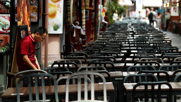 A restaurant promoter waits for customers at the largely empty Chinatown as tourism takes a decline due to the coronavirus outbreak in Singapore February 21, 2020 - Sputnik International