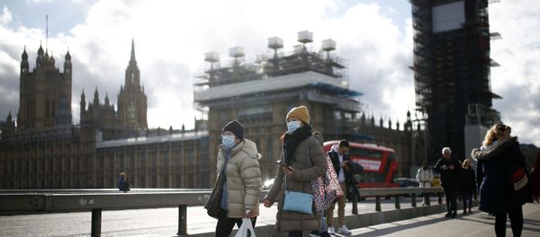 The Houses of Parliament can be seen as people wearing protective face masks walk across Westminster Bridge - Sputnik International
