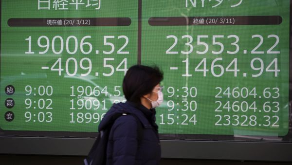 A woman walks past an electronic stock board showing Japan's Nikkei 225 and New York Dow index at a securities firm in Tokyo Thursday, March 12, 2020 - Sputnik International