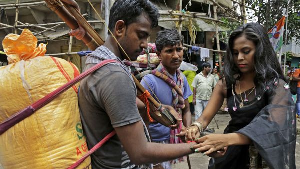 An Indian sex worker, right, ties a rakhi or a sacred thread on the wrist of a commuter as a symbolic gesture during Raksha Bandhan festival inside Sonagachhi, the biggest red light district in Kolkata, India, Monday, Aug. 7, 2017 - Sputnik International