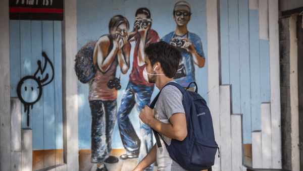 A man wears a face mask as he walks along a main street in Tel Aviv, Israel, Sunday, March 15, 2020 - Sputnik International