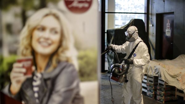 A man wearing protective gear sprays chemicals during the disinfection of a popular market, part of the efforts to limit the spread of the Coronavirus, in Bucharest, Romania, Sunday, March 15, 2020. For most people, the new coronavirus causes only mild or moderate symptoms. For some it can cause more severe illness - Sputnik International