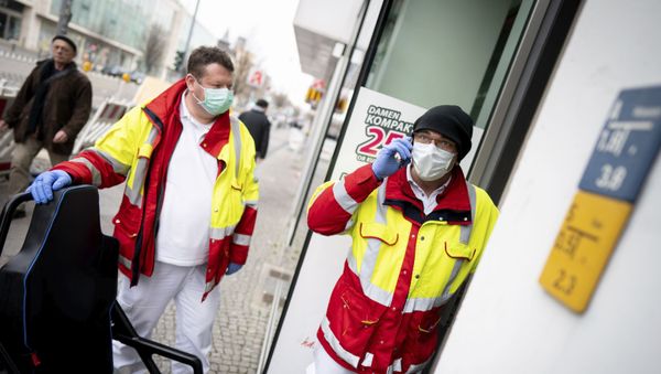 Paramedics from a patient transport company wearing face masks and gloves as they stand at the entrance to an apartment building to pick up a patient in the district Steglitz in Berlin, Germany, March 17, 2020 Paramedics from a patient transport company wearing face masks and gloves as they stand at the entrance to an apartment building to pick up a patient in the district Steglitz in Berlin, Germany, March 17, 2020 - Sputnik International