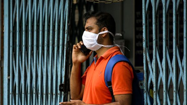 An Indian man wearing a mask talks on his mobile phone at a government run hospital where a special ward has been set aside for possible COVID-19 patients in Kolkata, India, Friday, March 6, 2020 - Sputnik International